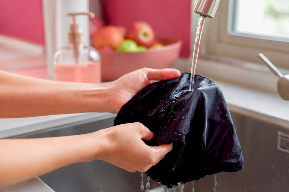 Hands rinsing period underwear in bathroom sink
