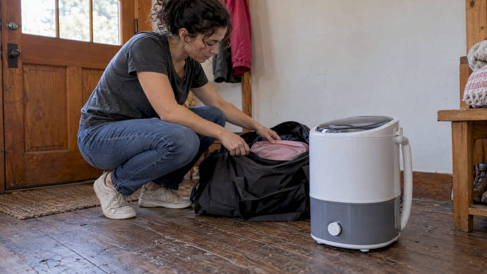 Traveler packing beside a compact portable washer