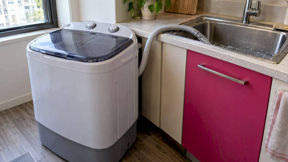 Mini washer draining through a hose into a sink