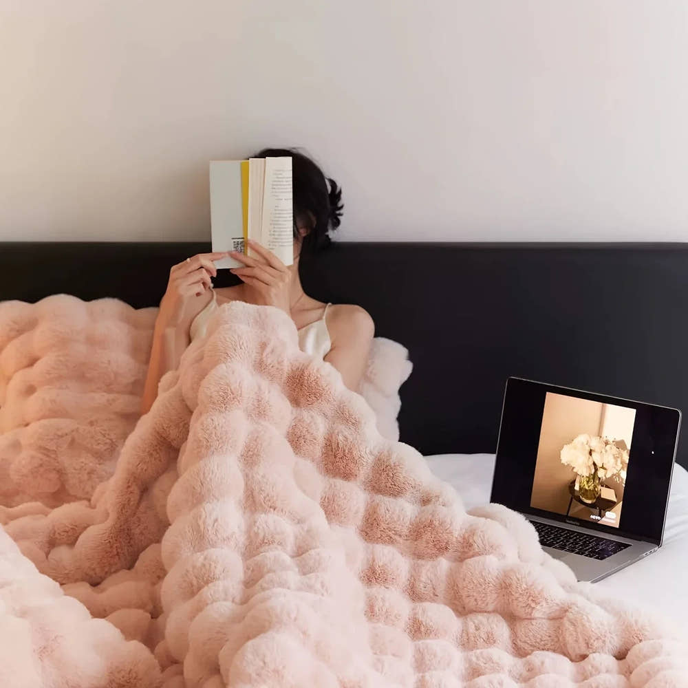 SweeTee Bubble Fleece Blanket in blush pink, shown draped on a bed (detail view)
