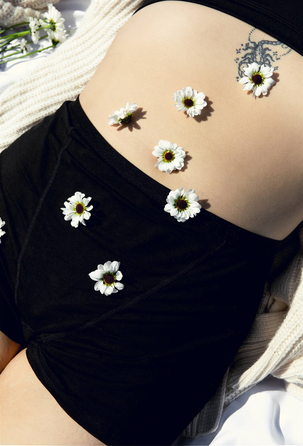 Close-up of model's hip in SweeTee black period underwear with daisies scattered on skin